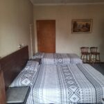 Comfortable bedroom with grey geometric bedding and a small table and chairs in Newton Park accommodation.