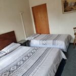 Bright bedroom with grey and white geometric bedding and built-in wooden cupboards at Newton Park accommodation.