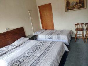 Bright bedroom with grey and white geometric bedding and built-in wooden cupboards at Newton Park accommodation.